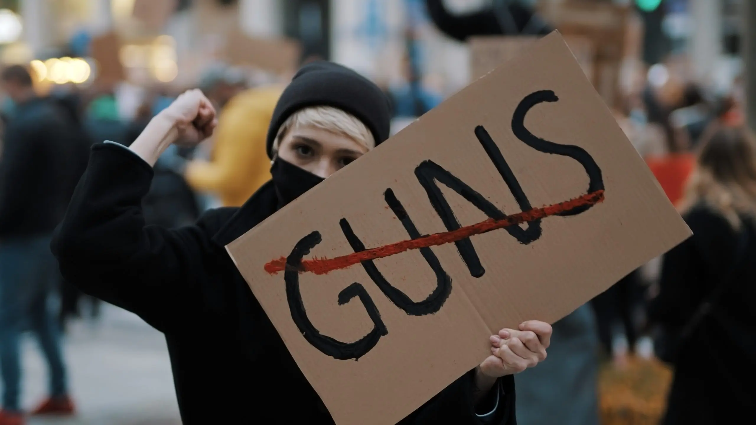 No guns. Young woman with face mask holding banner against gun violence. Demonstration and revolution concept