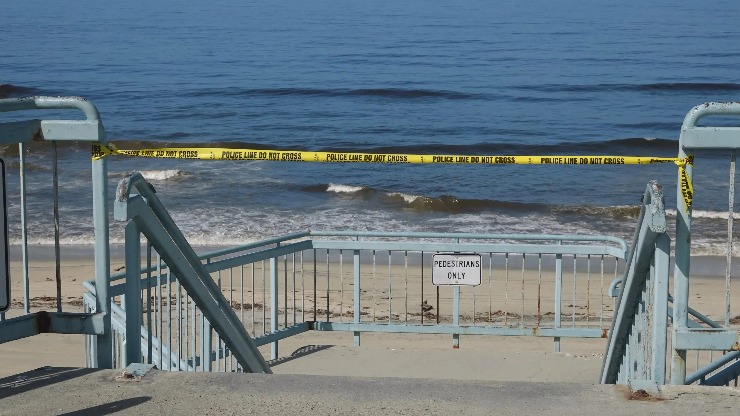Yellow police tape blocks access to a beach closed due to Covid 19 pandemic.