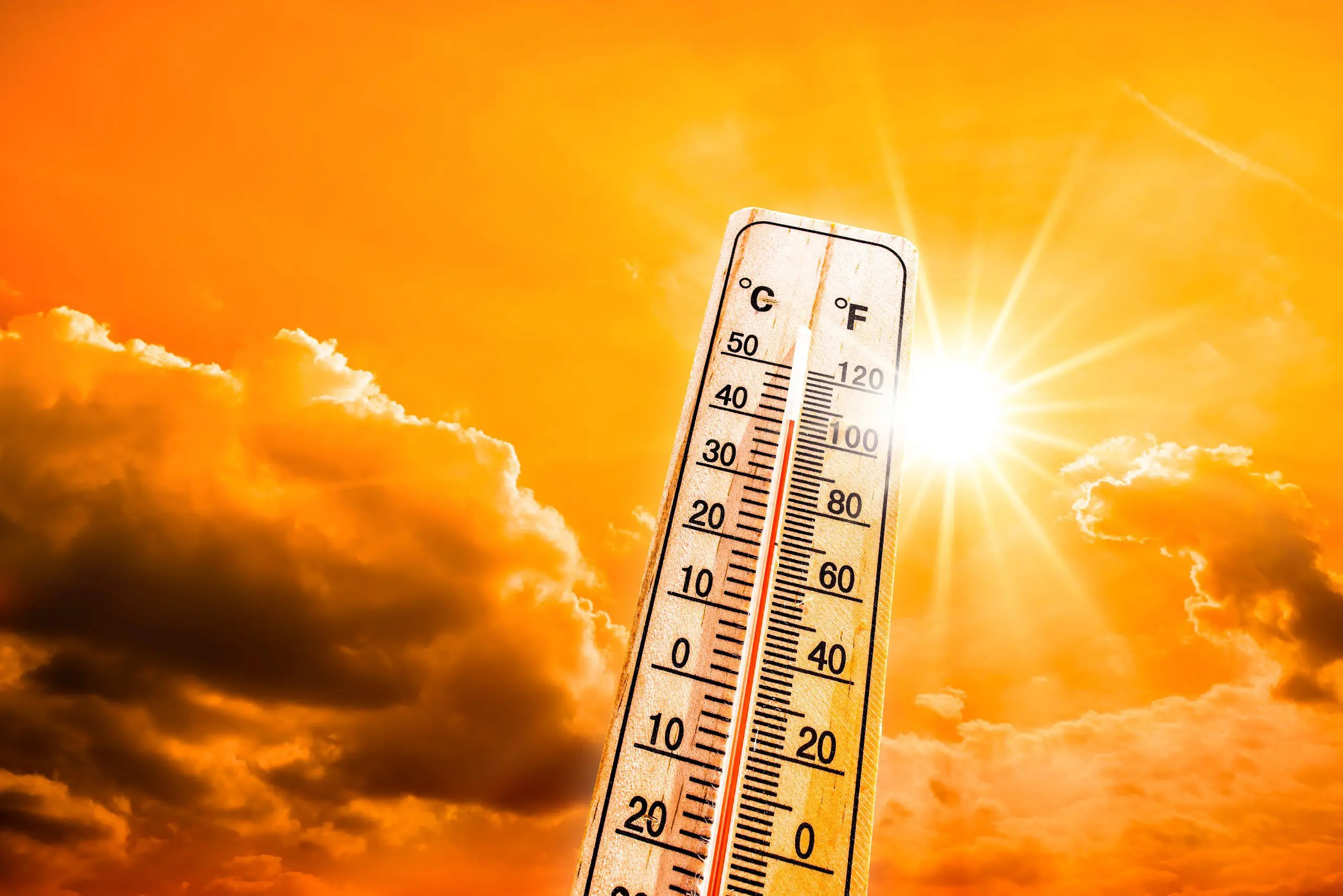 Hot summer or heat wave background, glowing sun on orange sky wi